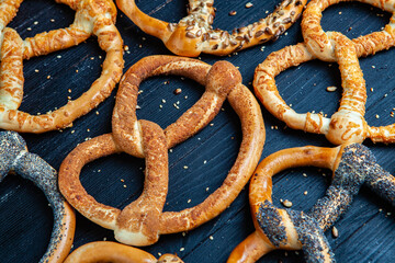 Fresh prepared homemade soft pretzels. Different types of baked bagels with seeds on a black background.