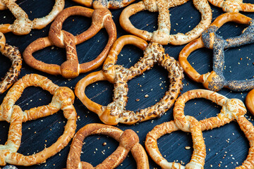 Fresh prepared homemade soft pretzels. Different types of baked bagels with seeds on a black...
