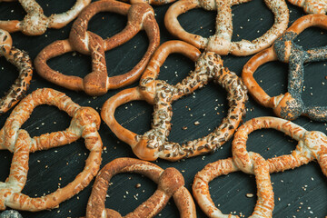 Fresh prepared homemade soft pretzels. Different types of baked bagels with seeds on a black background.