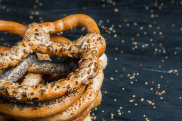 Fresh prepared homemade soft pretzels. Different types of baked bagels with seeds on a black background.