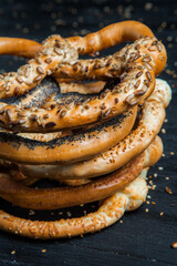 Fresh prepared homemade soft pretzels. Different types of baked bagels with seeds on a black background.