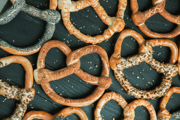Fresh prepared homemade soft pretzels. Different types of baked bagels with seeds on a black background.