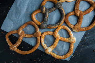Fresh prepared homemade soft pretzels. Different types of baked bagels with seeds on a black background.
