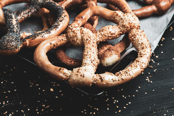Fresh prepared homemade soft pretzels. Different types of baked bagels with seeds on a black...