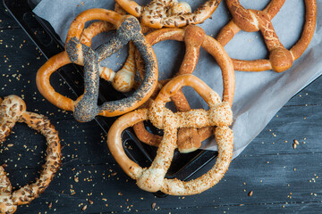 Fresh prepared homemade soft pretzels. Different types of baked bagels with seeds on a black background.