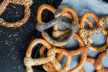 Fresh prepared homemade soft pretzels. Different types of baked bagels with seeds on a black background.