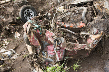 In the flood disaster, a car was dragged and badly damaged with garbage all around.