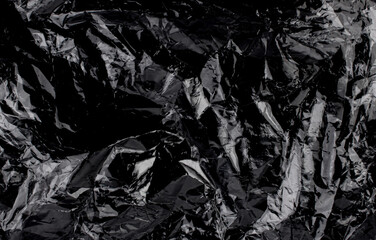 Wrinkled plastic wrap texture on a black background. Cellophane package wallpaper