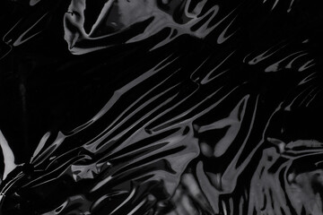 Wrinkled plastic wrap texture on a black background. Cellophane package wallpaper - obrazy, fototapety, plakaty