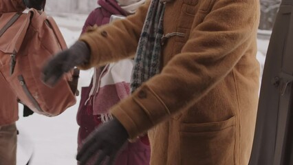 Medium slowmo shot of four young multiethnic friends packing car while getting ready for winter road trip