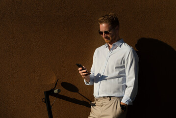 Young happy businessman outdoors. Portrait of handsome man using the phone.