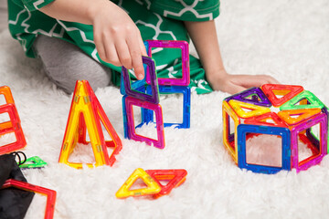 Young girl playing with magnetic colorful building block toys for learning