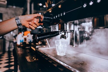 Barista making coffee with coffee machine in cafe.