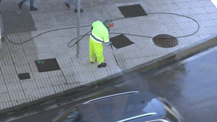 Sweeper cleaning a city sidewalk with high pressure washing machine