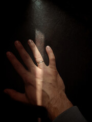 Man's hand with a ring on the ring finger of a leather sofa