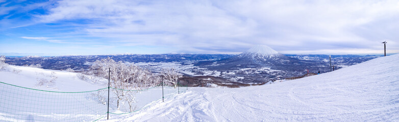 Fototapeta na wymiar Panoramic view of snowy volcano and town seen from a ski resort (Niseko, Hokkaido, Japan)