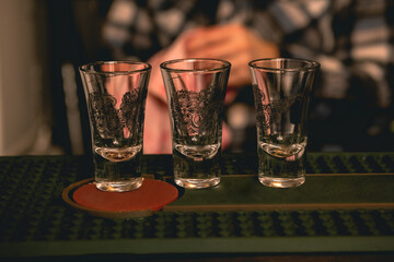 Three empty shot glasses on bar counter for serving alcoholic drinks
