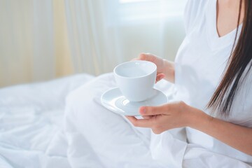 Fototapeta na wymiar Asian woman drinking coffee in the morning in bed.
