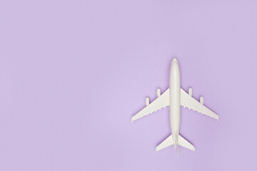 Airplane model. White plane on purple background. Travel vacation concept. Summer background. Flat lay.