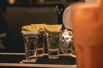 Three rimmed with salt tequila shots with lime on bar counter