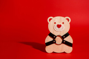 Cute teddy bear with bdsm straps on red background. Valentine's day celebration, creative idea