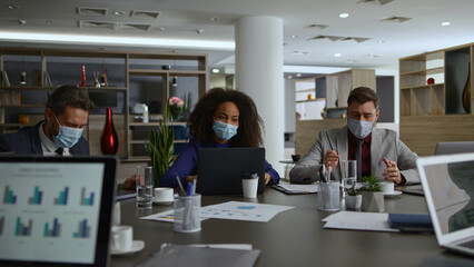 Multiracial business group talk share ideas. Coworkers wear covid safety masks.