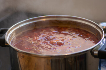 A boiling pot of traditional sour Borscht soup,  one of the most famous dishes of Ukrainian cuisine, made with beetroots as one of the main ingredients, which give the dish its distinctive red color