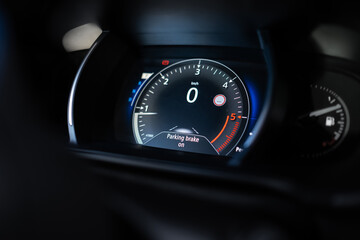 Modern car dashboard shows parking brake on message. Zero kilometre