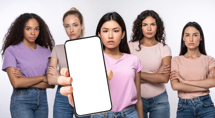 Serious ladies showing blank empty smartphone screen for mockup