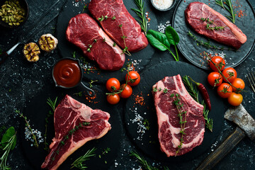 A variety of raw beef steaks for grilling with seasonings: T-bone, striploin steak, ribeye. Top...