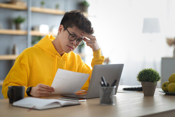 Asian man holding paper reading report working on pc