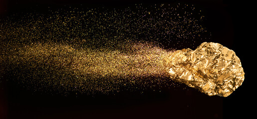 Piece of gold or golden nugget with visible gold shining comet tail ath the dark background.