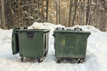 Two green garbage cans in with snow on top in winter. Outdoors