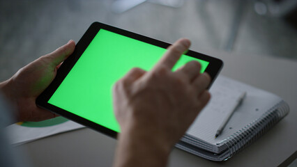 Businessman swiping tablet pad green screen analyzing corporate data in office.
