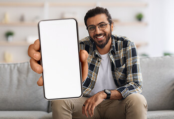 Cheerful Indian Guy Showing Smartphone With Big Blank White Screen At Camera