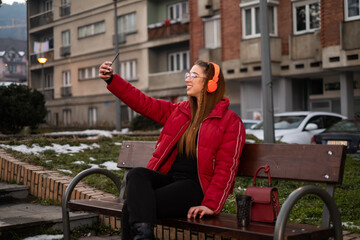 young girl on a bench takes a photo of herself