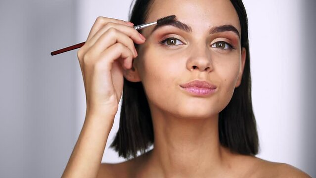 Beautiful woman using brush for eyebrows and applies wax, does correction of eyebrows. Beauty and Skin care concept
