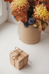 A gift box and bouquet of flowers in box - surprise for birthday or mother's day or valentine. Flowers bouquet and gift box in craft paper eco packaging. Autumn style floral bouquet.