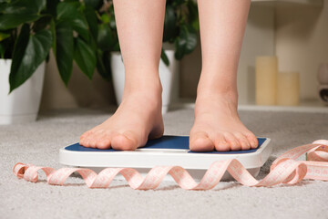 Women's bare feet on floor scales and measuring tape, the concept of losing weight.
