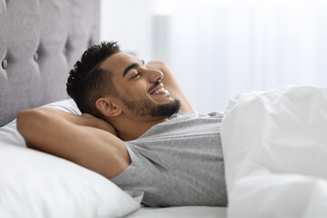 Morning Relax. Smiling Pleased Arab Man Lying In Bed After Waking Up