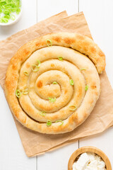 Banitsa - traditional Bulgarian spiral shape pie with brynza cheese and green onion are on white...