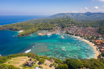 Fototapeta na wymiar Dramatic aerial view of the Padang Bai village and harbor in east Bali in Indonesia. Silayukti temple in the foreground is one of the holiest Balinese Hindu temple in the area