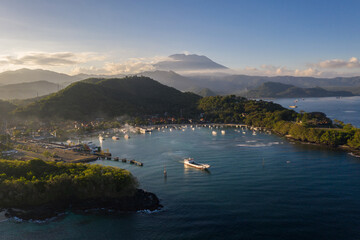 Dramatic view of a boat leaving the Padang Bai harbor in eastern Bali with the Agung volcano in the background at sunset in Indonesia