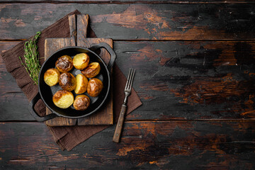 Baked potatoes with herbs and garlic , in frying cast iron pan, on old dark  wooden table...