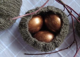 Bronze Easter eggs in the knitted nest, rustic decor