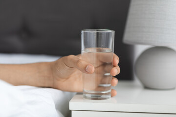 Male Hand Taking Glass With Water From Bedside Table At Home