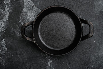 Vintage cast iron skillet with copy space for text or food with copy space for text or food, top view flat lay , on black dark stone table background - obrazy, fototapety, plakaty