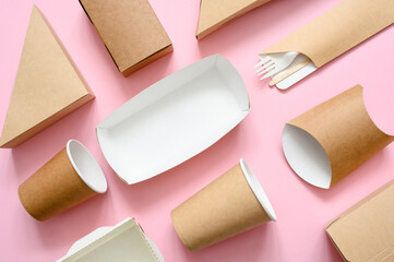 A lot of disposable paper eco-friendly tableware is stacked evenly on a pink background. Tableware made of brown biodegradable paper.