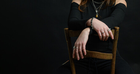Hands - close-up. A young girl sitting on an old chair. She put her hands on the back of the chair. Rings, bracelet
