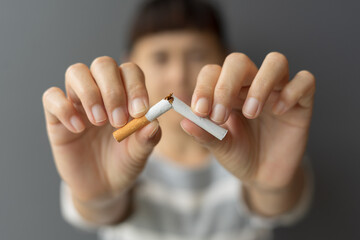 Portrait young woman holding broken cigarette in hands. Happy female quitting refusing smoking...